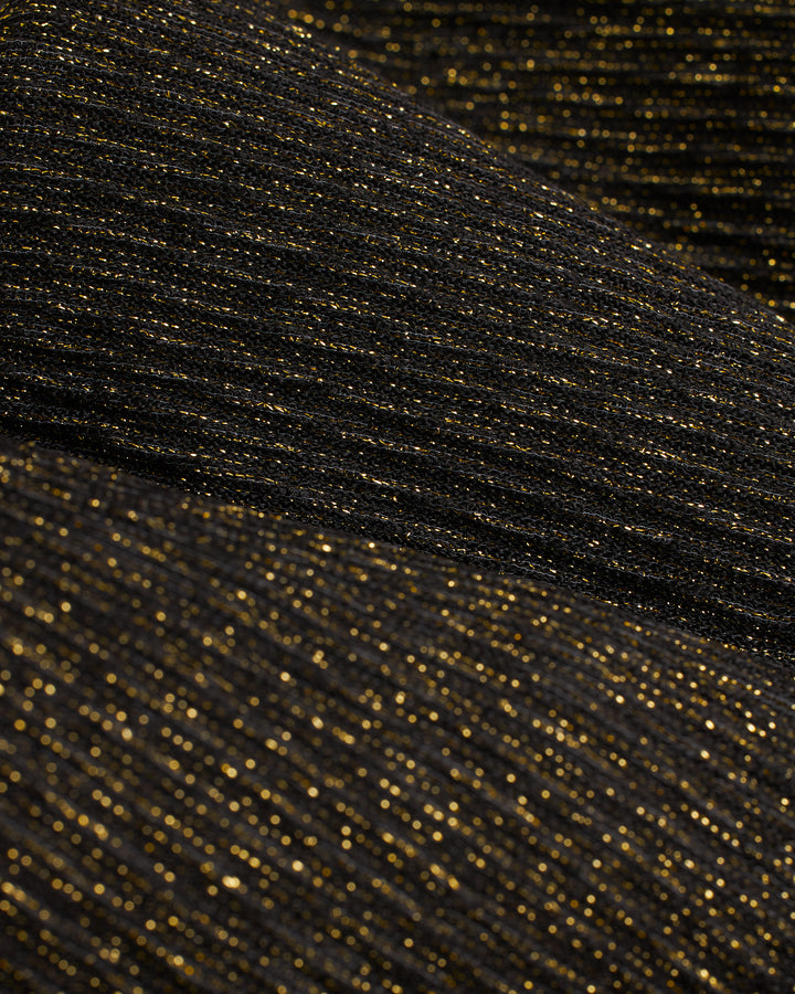 A close up of the Dandy Del Mar Hydra Sheer Shimmer Pant - Onyx, a black and gold fabric with a shimmer effect.
