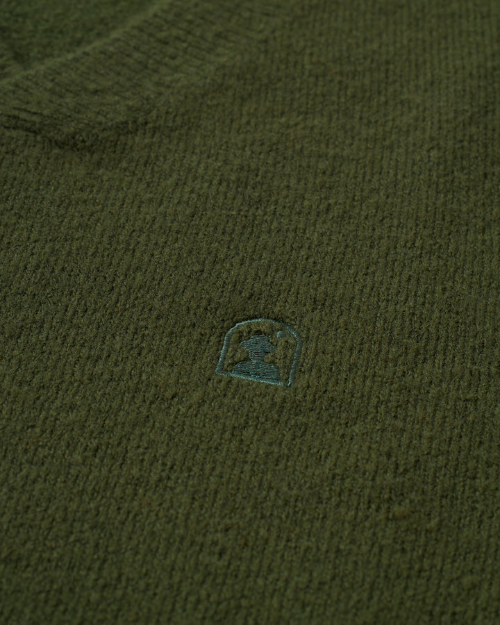 A close up of The Lima Sweater - Selva by Dandy Del Mar with a small logo on it.