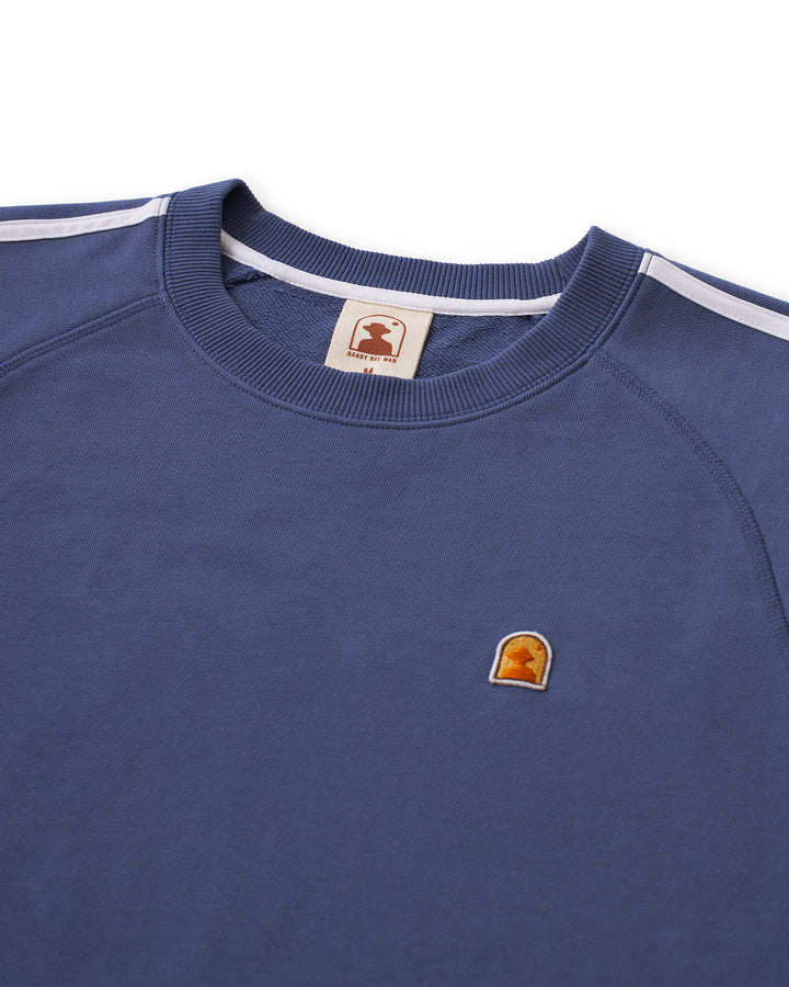 A blue Marseille Pullover - Moontide with an orange logo on it.