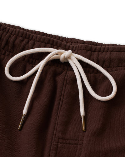Close-up of The Marseille French Terry Shorts - Carajillo by Dandy Del Mar, showing the brown waistband and off-white drawstring with gold metal tips tied in a bow.