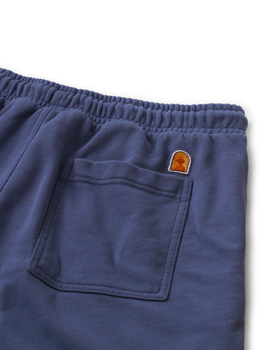 Close-up of The Marseille French Terry Shorts - Moontide by Dandy Del Mar, featuring an elastic waistband, a back pocket, and a small embroidered patch above the pocket.