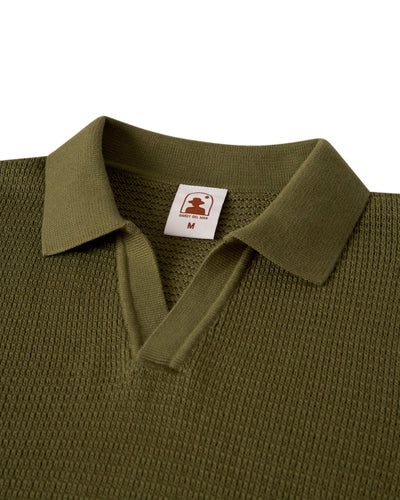 The Sebastian LS Polo Shirt - Arbequina by Dandy Del Mar: an olive green, sweater-knit cotton long sleeve polo with a split neckline and visible "M" tag—part of our knitwear collection.