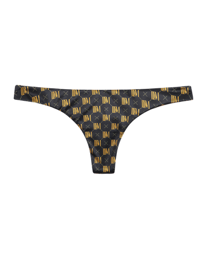 The Gomera Bottom - Oro Monogram by Dandy Del Mar: black thong underwear with gold DDM Monogram and "X" details, offering cheeky coverage for a bold, stylish look. Displayed on a plain background.