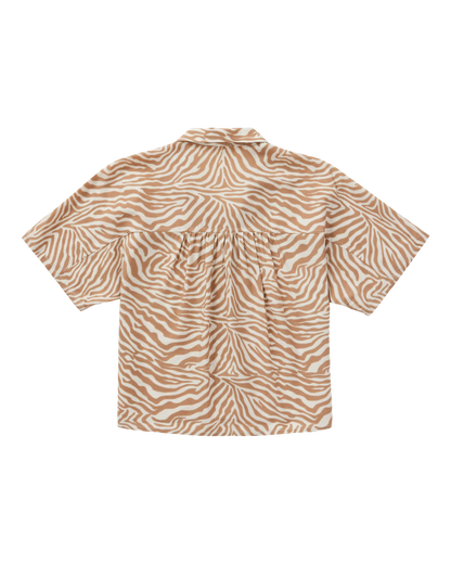 The Lucia Top - Cortado Sawla Print by Dandy Del Mar is a cropped, short-sleeve button-down linen shirt with a beige and white zebra print, shown from the back on a black background.