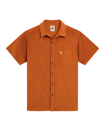 The Dandy Del Mar Tropez Terry Cloth Shirt in Burnt Sienna features short sleeves, a button-up front, relaxed tailored fit, chest pocket, and small logo tag, shown on a white background.