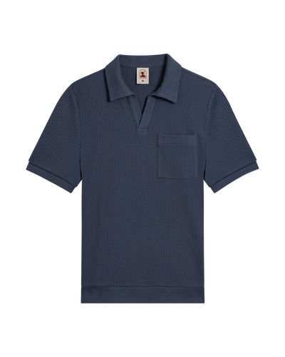 The Dandy Del Mar Cannes Waffle Knit Polo Shirt in Moontide, short-sleeve with an open collar, chest pocket, and hidden buttons, features waffle knit fabric and is shown laid flat on a white background.