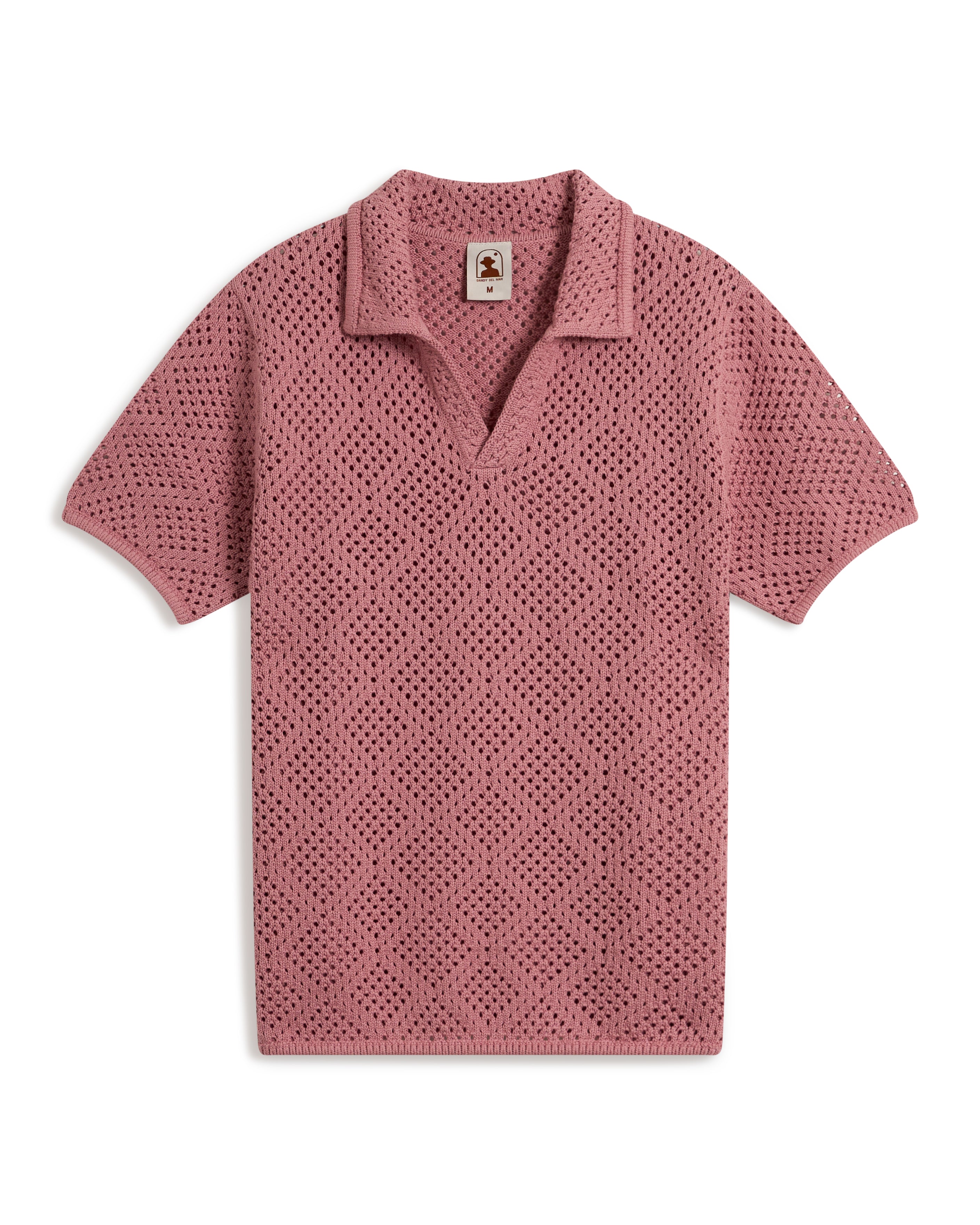 A short-sleeved, V-neck crochet polo shirt in pink, featuring a collar, called "The Antibes Crochet Shirt - Dawn" by Dandy Del Mar, displayed on a plain white background.