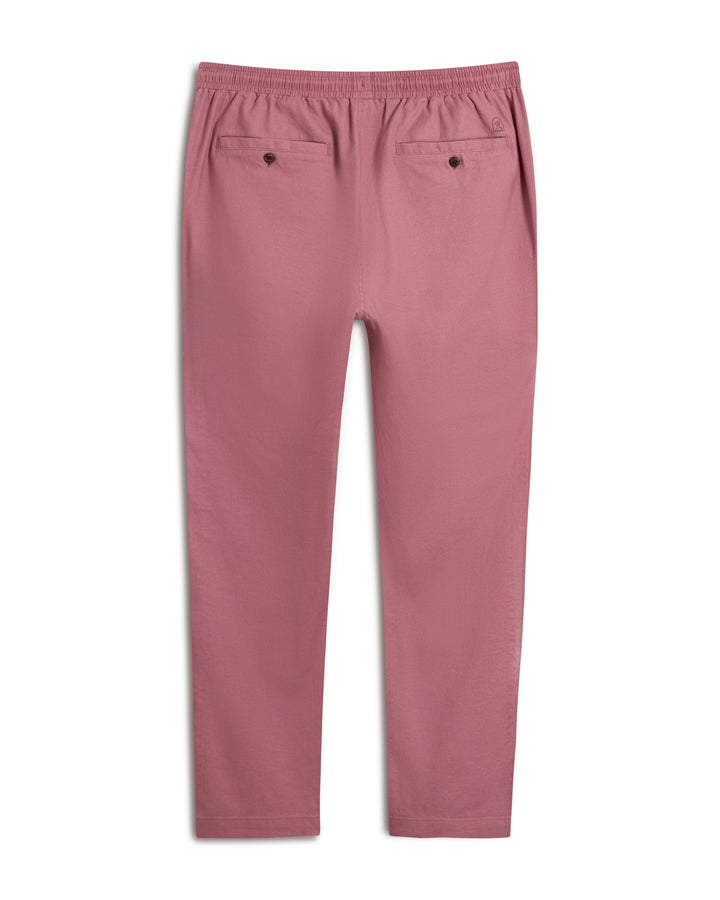 The Brisa Linen Pant - Dawn by Dandy Del Mar in a soft pink features an elastic waistband for comfort and style, ideal for vacation wear. With two back pockets, they are showcased flat on a white background, highlighting their relaxed charm.