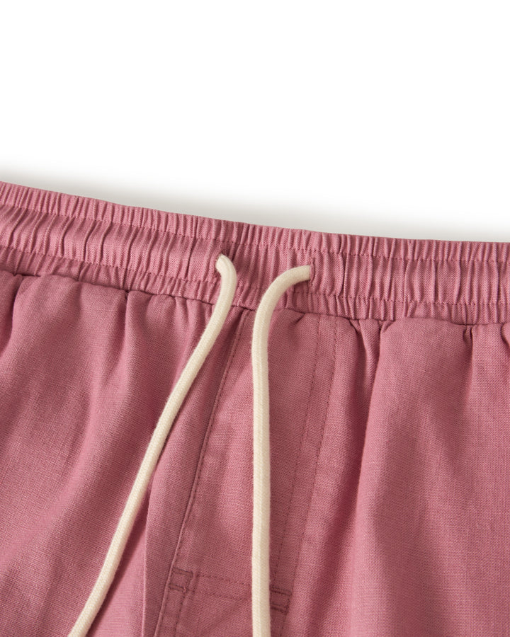 Close-up of The Brisa Linen Pant - Dawn by Dandy Del Mar, showcasing pink vacation pants with an elastic waistband and white drawstring.