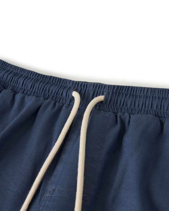 Close-up of The Brisa Linen Pant in Moontide by Dandy Del Mar, featuring a navy blue elastic waist and beige drawstring, perfect for vacation vibes.