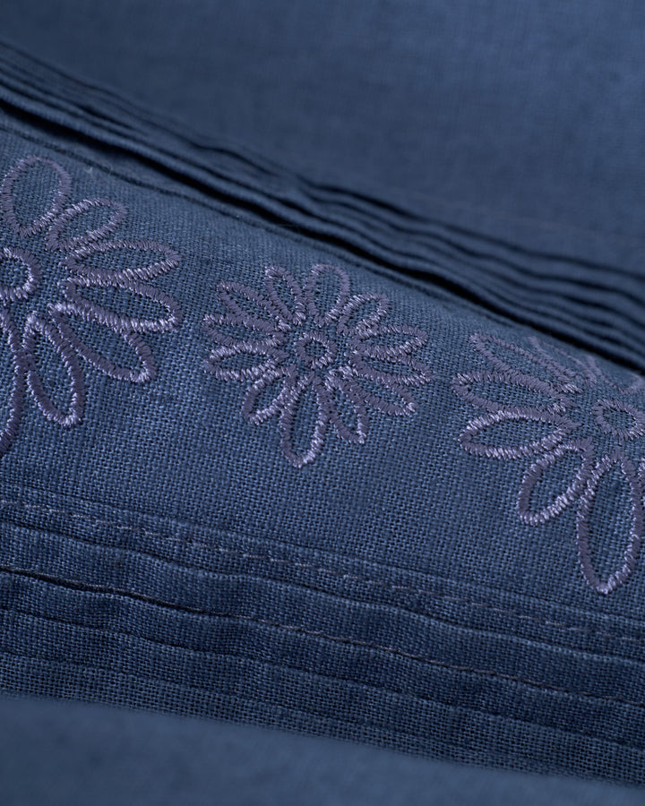 Close-up of Moontide fabric from The Brisa Linen Shirt by Dandy Del Mar, featuring embroidered floral patterns and pleated details.