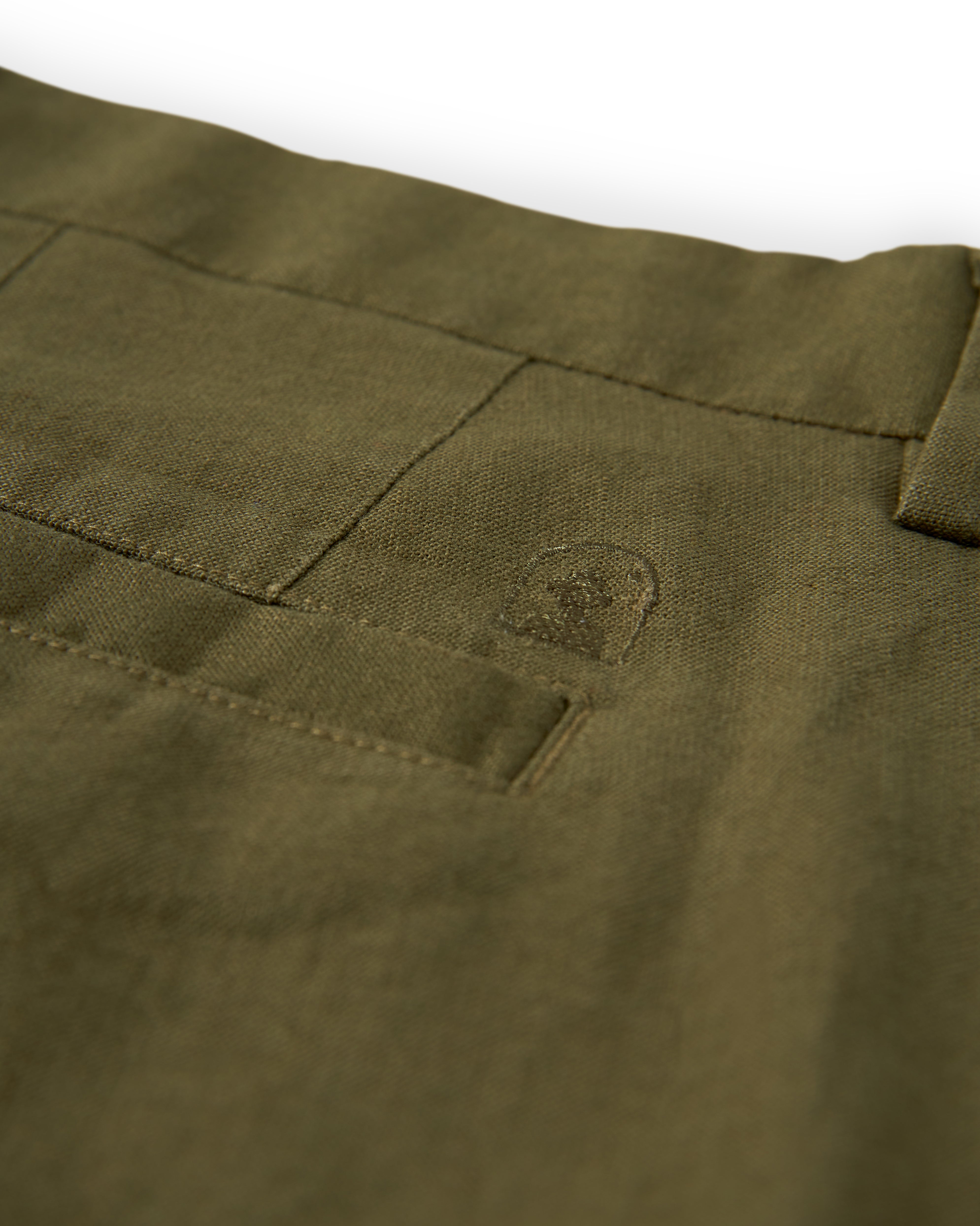 Close-up of an olive green fabric with visible stitching and a small, embroidered design, reminiscent of the fine texture found in The Brisa Linen Trouser - Berdea by Dandy Del Mar.