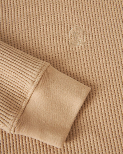 Close-up of Dandy Del Mar’s The Cannes LS Waffle Knit Shirt in Truffle, showcasing its beige ribbed waffle fabric, sleeve cuff, and small embroidered chest logo.