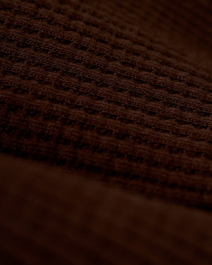 A close-up view of the brown 100% cotton fabric with a waffle weave pattern, reminiscent of the exquisite texture found in Dandy Del Mar's The Cannes Waffle Knit Robe - Carajillo.