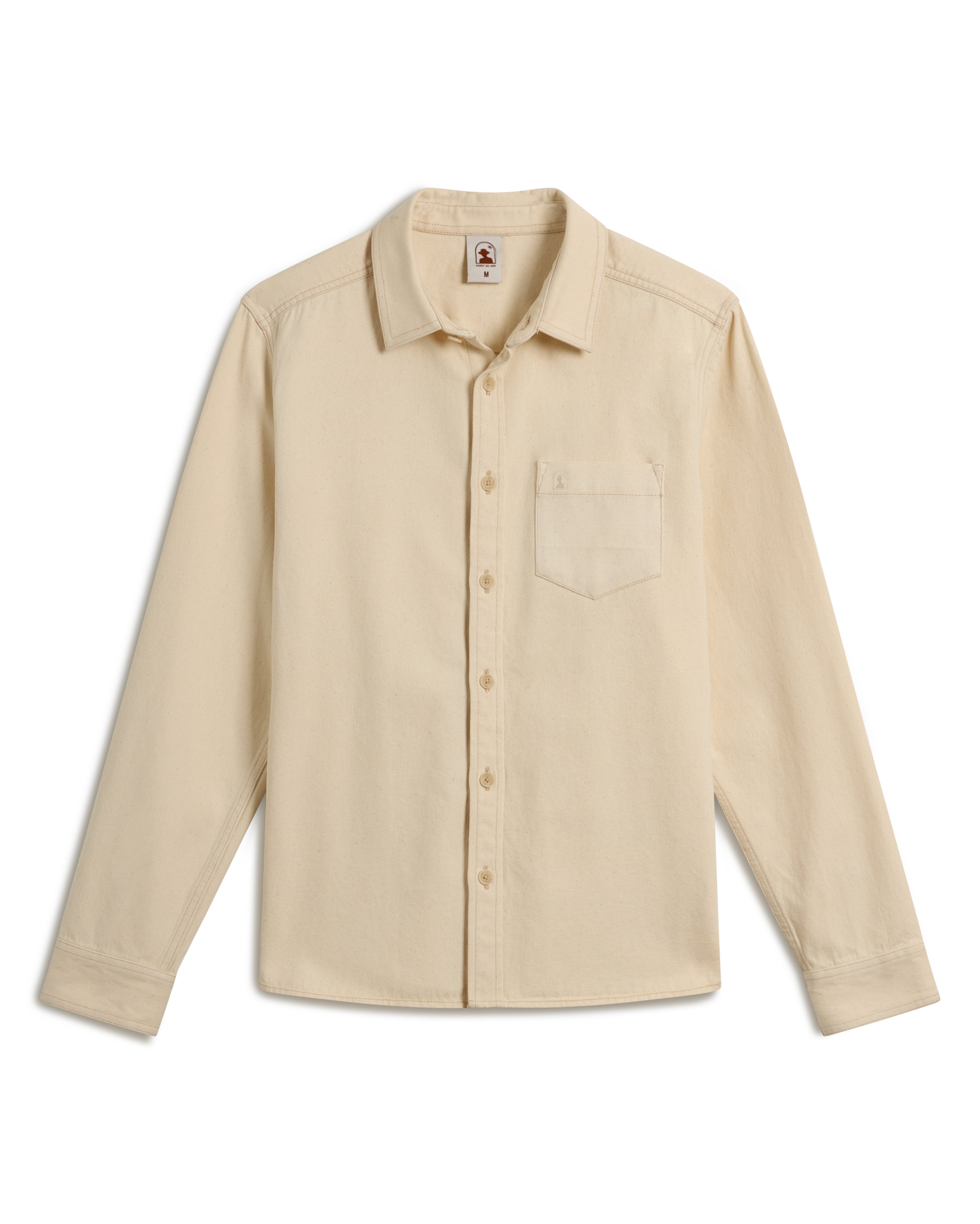 The Cartagena Denim Shirt - Scallop by Dandy Del Mar is a beige long-sleeve button-up with a chest pocket, laid flat.