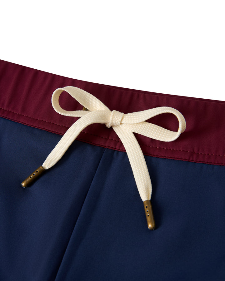 Close-up of The Cassis Square-Cut Swim Brief - Anchor by Dandy Del Mar featuring a maroon waistband, navy fabric, and a white drawstring bow in the center.