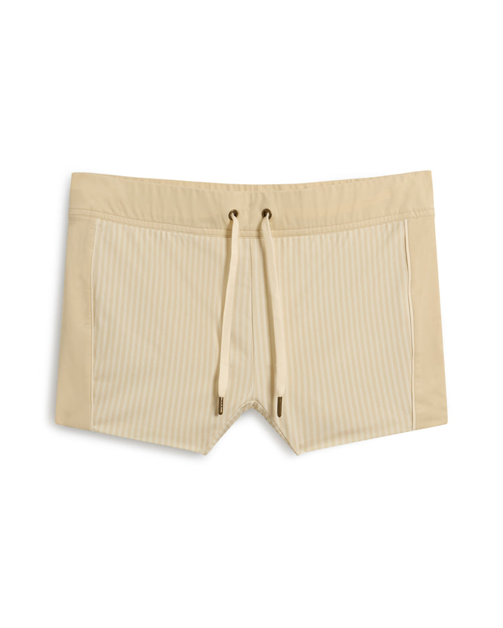 The Cassis Square-Cut Swim Brief - Sabbia by Dandy Del Mar features beige swim trunks with vertical stripes and a drawstring waistband.