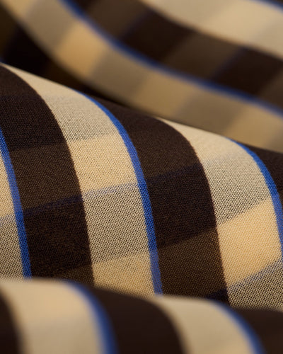 Close-up of The Curacao Shorts - Tierra by Dandy Del Mar, relaxed fit chiffon shorts in brown and beige checkered pattern with thin blue vertical lines.