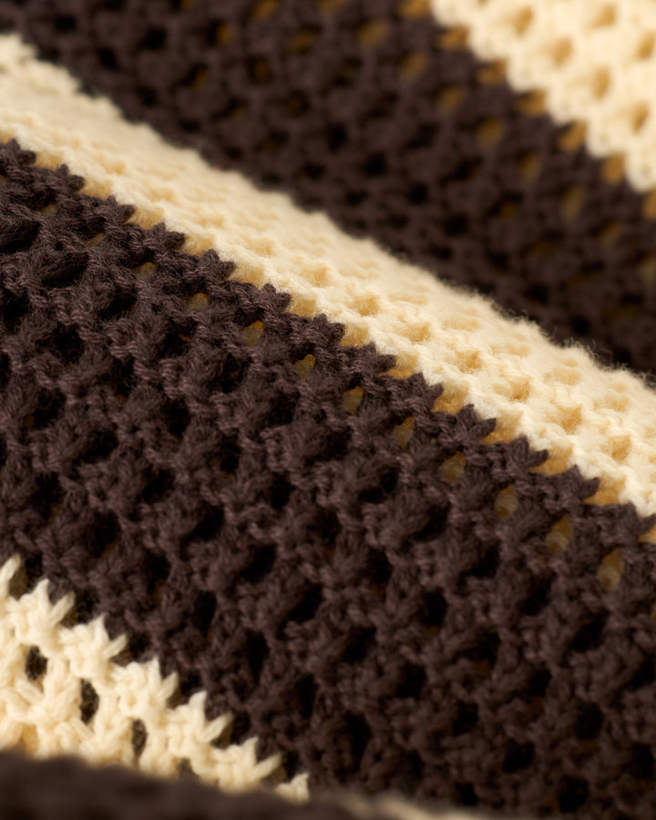 Close-up of The Dominica Crochet Shirt - Tierra by Dandy Del Mar, featuring a knitted fabric with alternating brown and cream stripes in a repetitive openwork pattern.