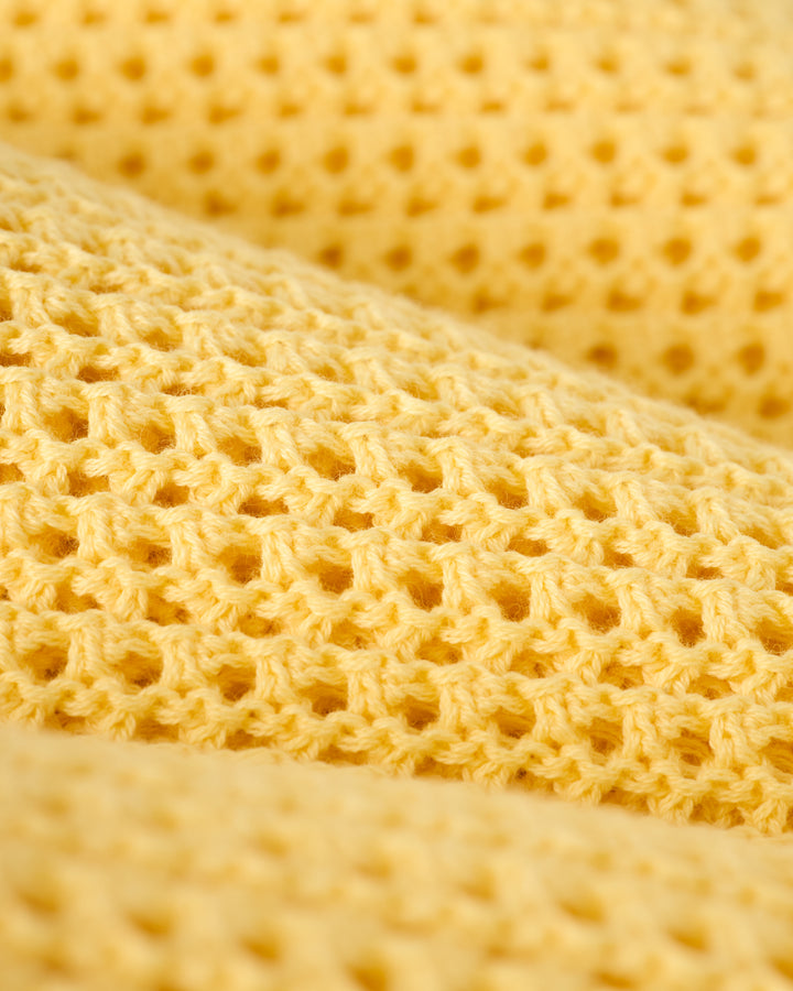 Close-up of Dandy Del Mar's Dominica Crochet Tank in Plantain, featuring a yellow honeycomb-patterned textured fabric, ideal for a lightweight crochet top.