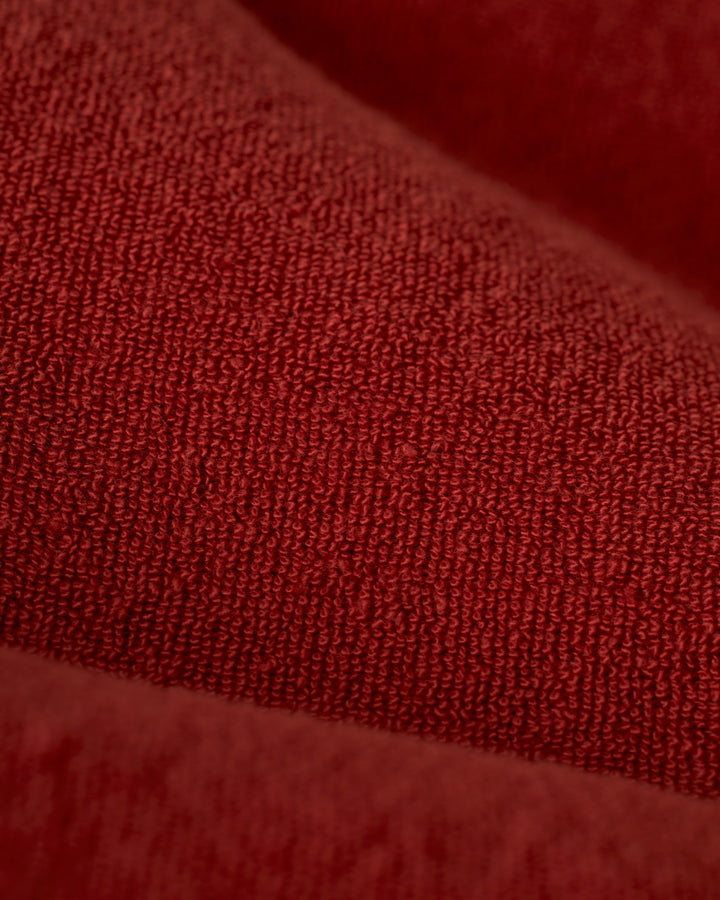 Close-up of The Gaucho Terry Cloth Shirt - Rouge by Dandy Del Mar, showcasing its red, ultra-soft terry cloth fabric with detailed weave and soft surface.