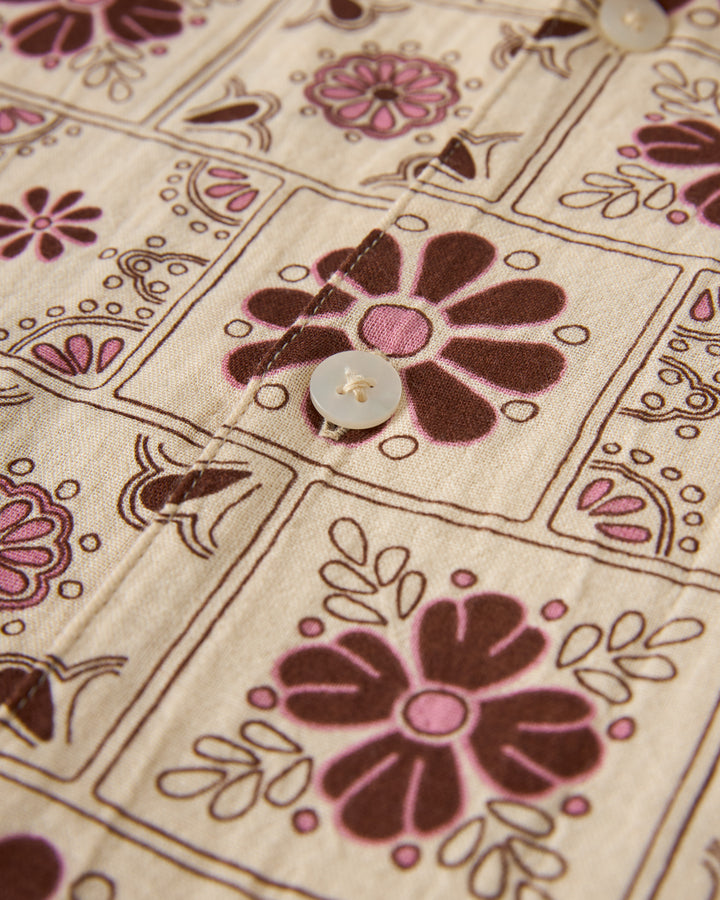 Close-up of The Grenadine Crinkle Gauze Shirt - Sabbia by Dandy Del Mar, showing brown and pink floral square sections with buttons along the seam.