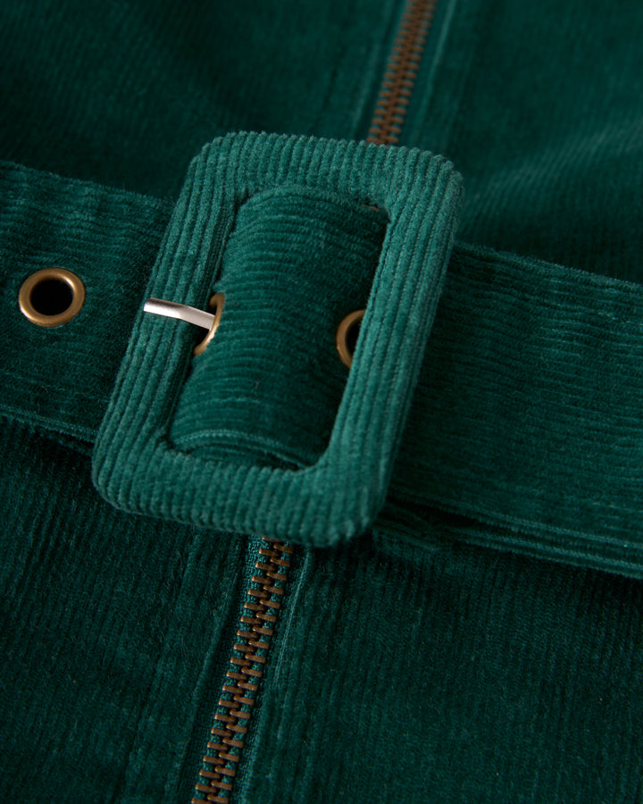 Close-up of The Kitts Corduroy Dress - Albero by Dandy Del Mar, featuring a green corduroy waist belt with a rectangular buckle that perfectly complements the slim fit of the garment.