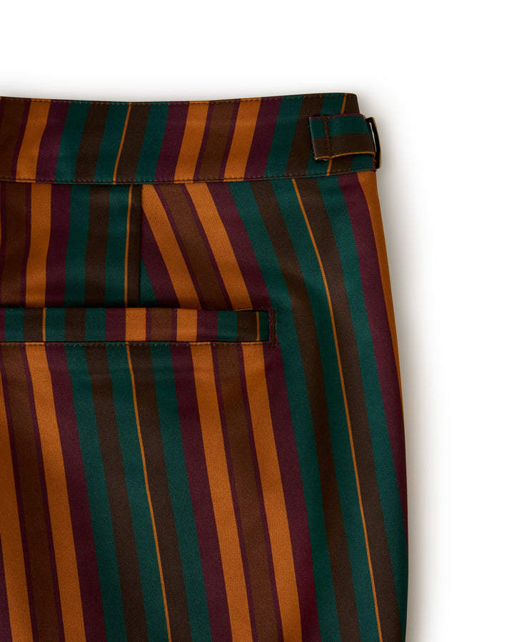 Close-up of The Mallorca Swim-Walk Short by Dandy Del Mar, featuring striped fabric in green, orange, red, and burnt sienna with a belt loop and horizontal back pocket.  .