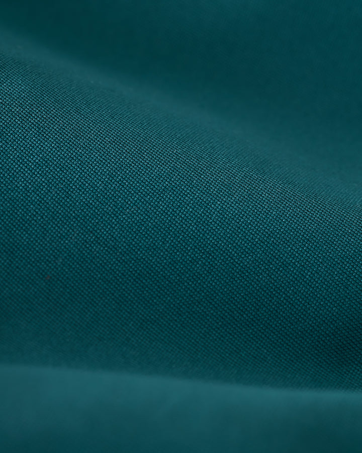 Close-up of a teal fabric with fine texture and visible weave pattern, akin to the high-quality construction of Dandy Del Mar’s Mallorca Swim-Walk Short in Tempest Blue.