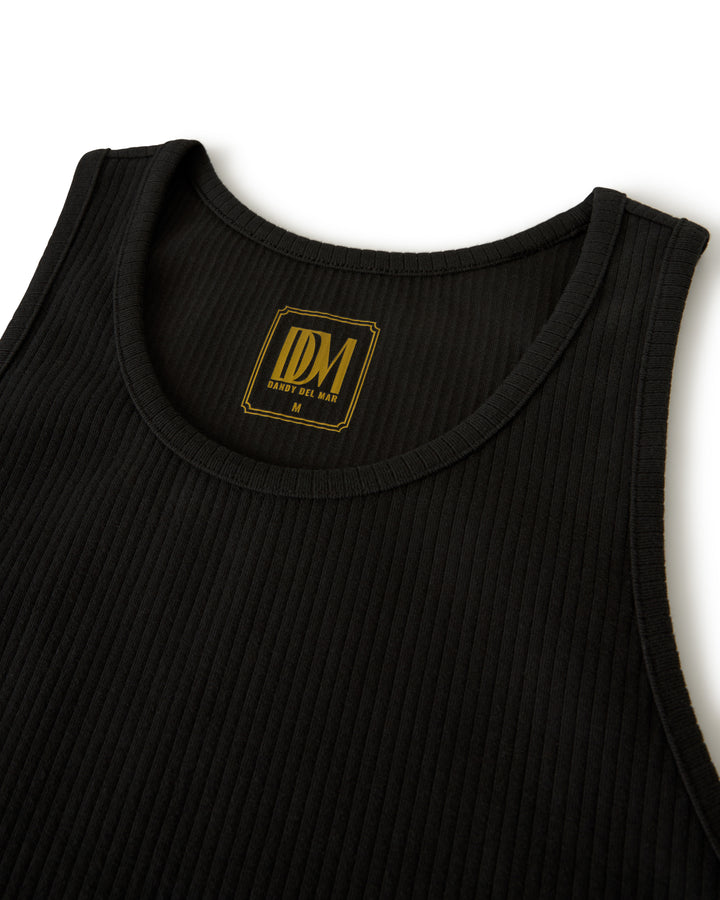 A black ribbed sleeveless shirt named "The Milan Rib Tank - Onyx" from Dandy Del Mar features a label with "IDM" and "MEDIUM.