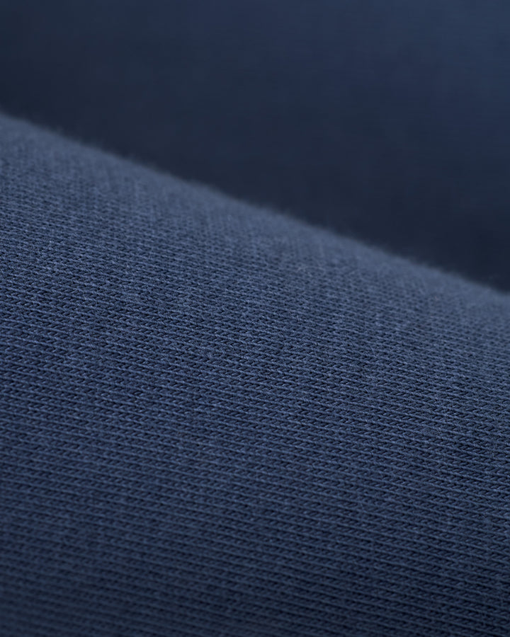 Close-up of dark blue fabric, displaying a fine knit texture with evenly spaced threads, ideal for crafting The Nassau Tee - Moontide by Dandy Del Mar.