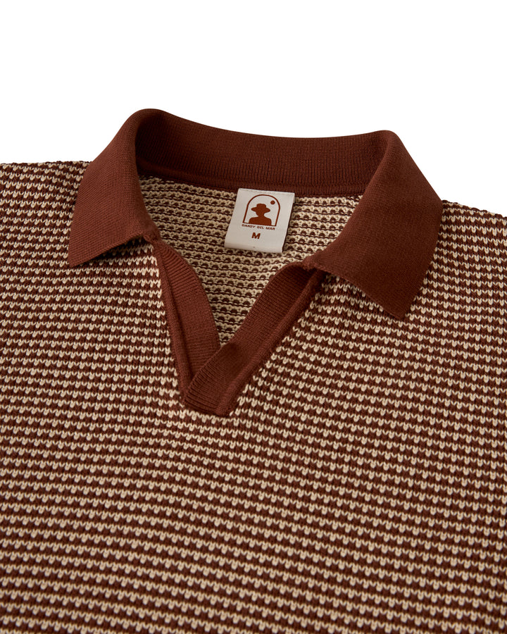 The Palamos Knit Polo Shirt by Dandy Del Mar is a brown and beige textured short-sleeve polo with a collar and an inside tag displaying the logo and size "M".