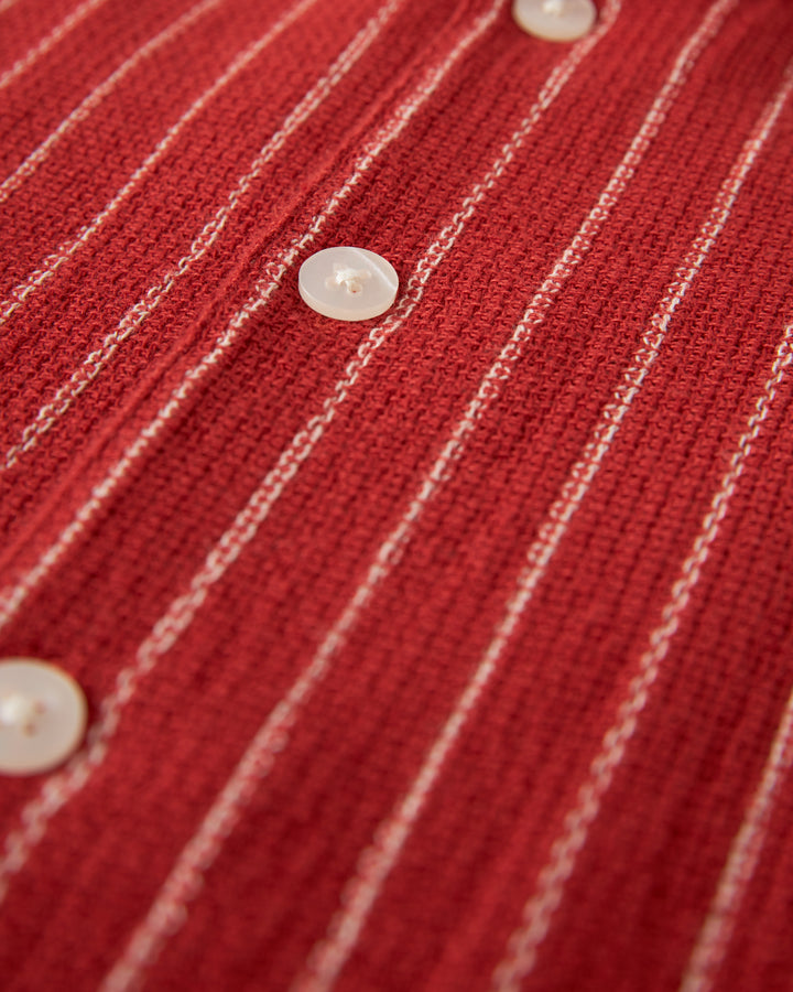 Close-up of The Palma Shirt - Garam by Dandy Del Mar, featuring red fabric with white vertical stripes, white buttons, and a distinctive camp collar.