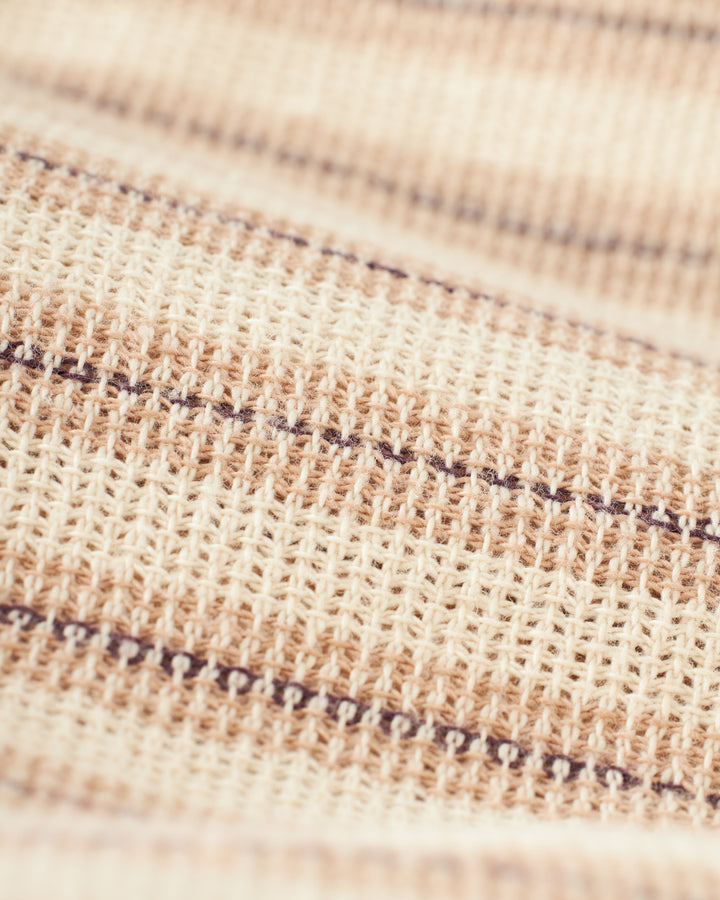 Close-up of the Palma Shirt - Scallop by Dandy Del Mar, featuring horizontal beige and brown stripes, highlighting the detailed texture and thread pattern of its soft burlap-textured fabric.