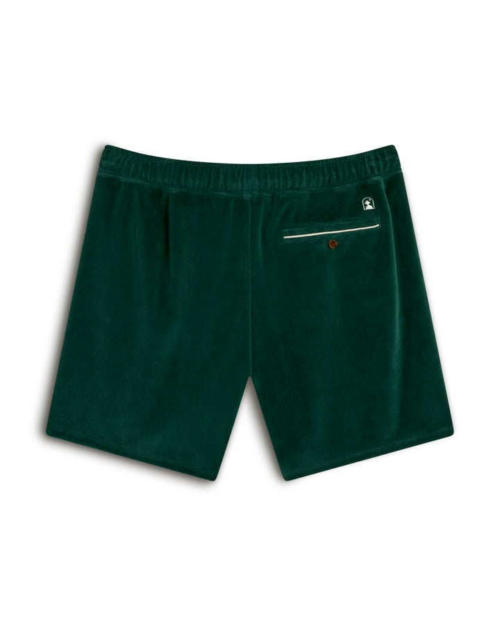 The Rio Velour Short - Albero by Dandy Del Mar features green velvet fabric with an elastic waistband, one back pocket with a button, and a small logo patch above.