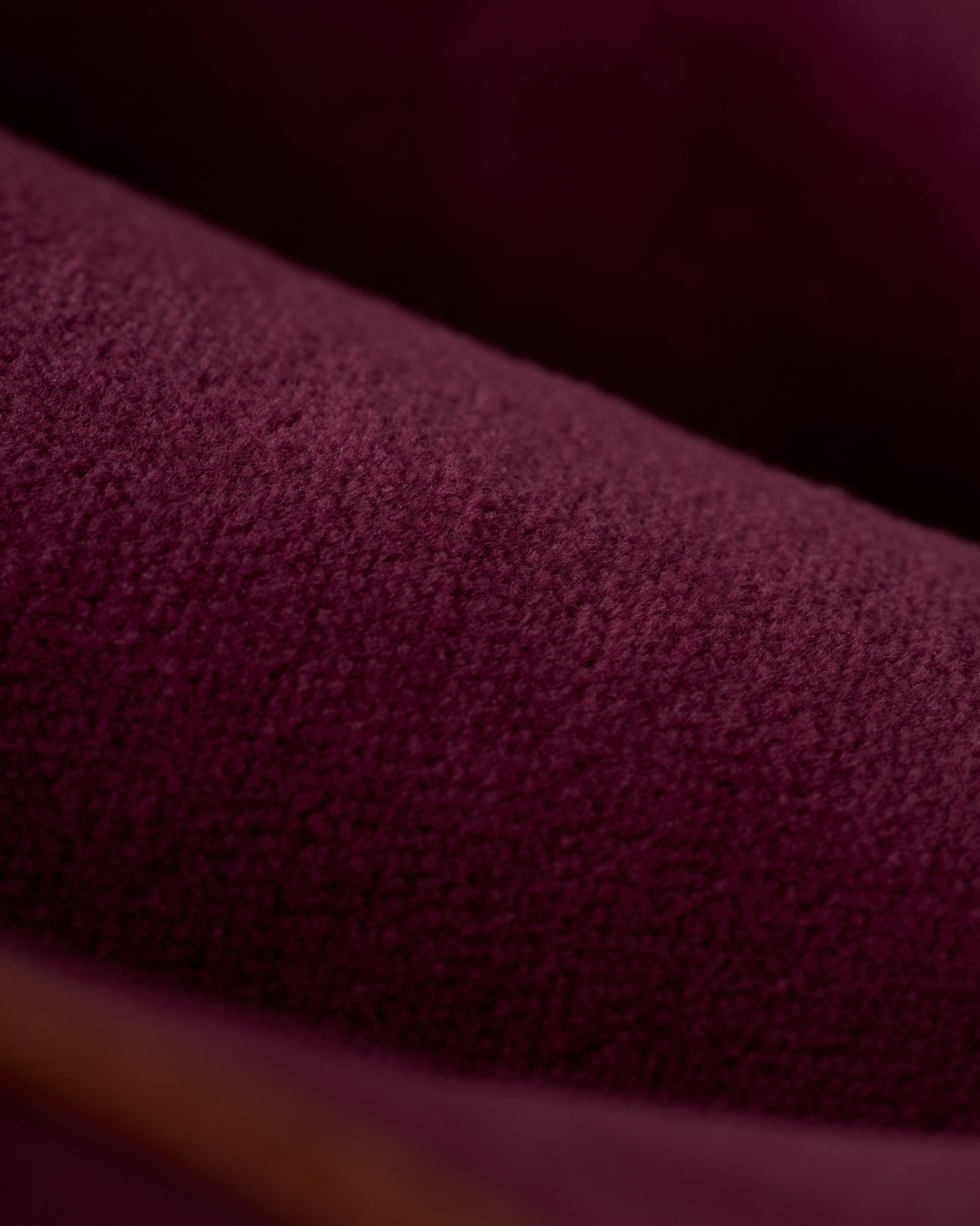 Close-up of richly textured Bordeaux velour fabric with soft folds and visible fibers, featured in Dandy Del Mar’s The Rio Velour Short, an athletic leisurewear piece with an elastic drawcord waist.