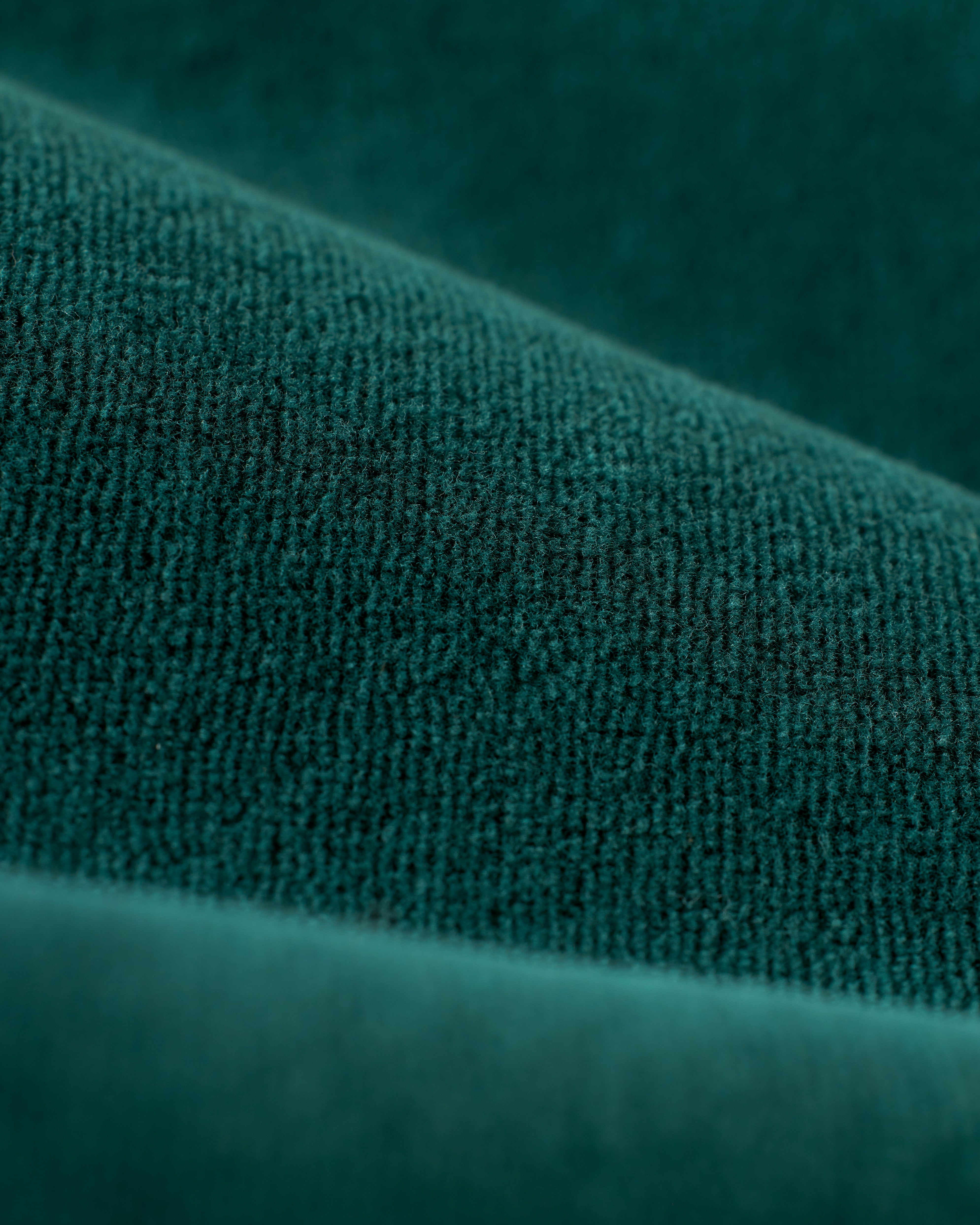 Close-up image of green textured fabric folds, reminiscent of the luxurious Rio Velour Jacket - Albero by Dandy Del Mar, showing a detailed view of the material's fibers and surface.