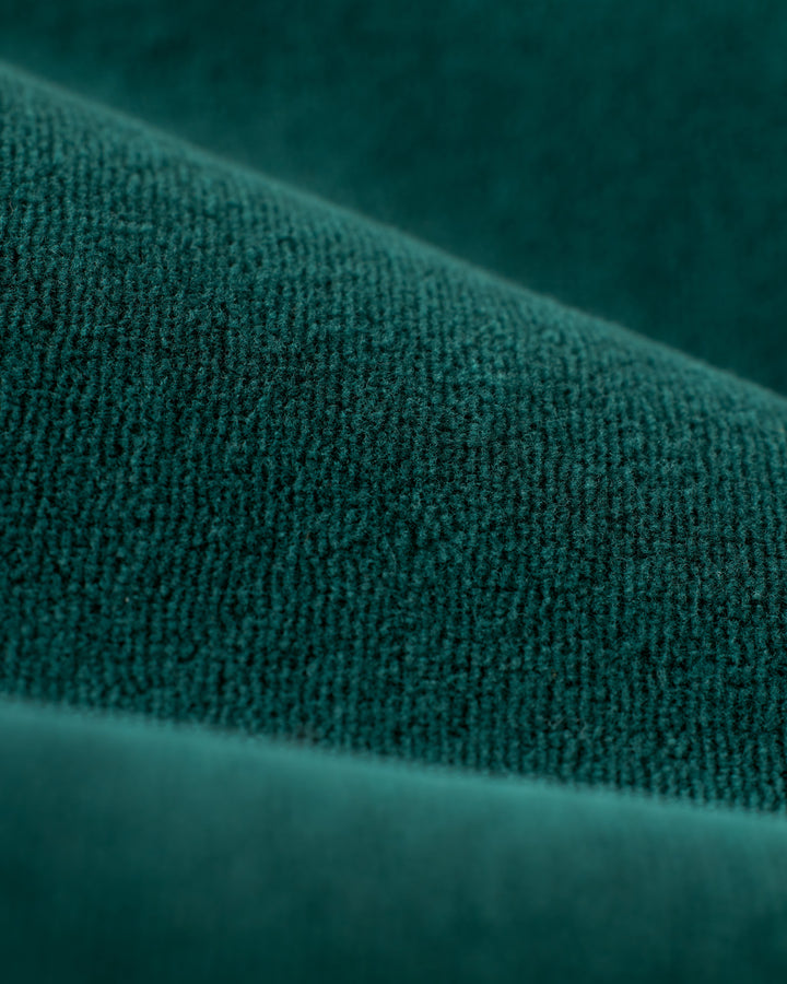 Close-up image of a deep green, textured fabric with visible folds and a plush surface, reminiscent of Dandy Del Mar's The Rio Velour Pant - Albero, perfect for athletic leisure.