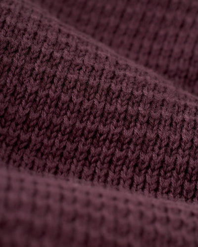Close-up of The Sebastian LS Polo Shirt in Amethyst by Dandy Del Mar, highlighting the maroon waffle-knit texture and soft folds that showcase its premium quality.