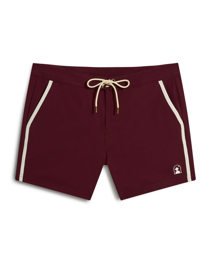 The Stirata Swim Short - Bordeaux by Dandy Del Mar features a tan drawstring waist, white trim, pockets, and a small logo on the left leg.