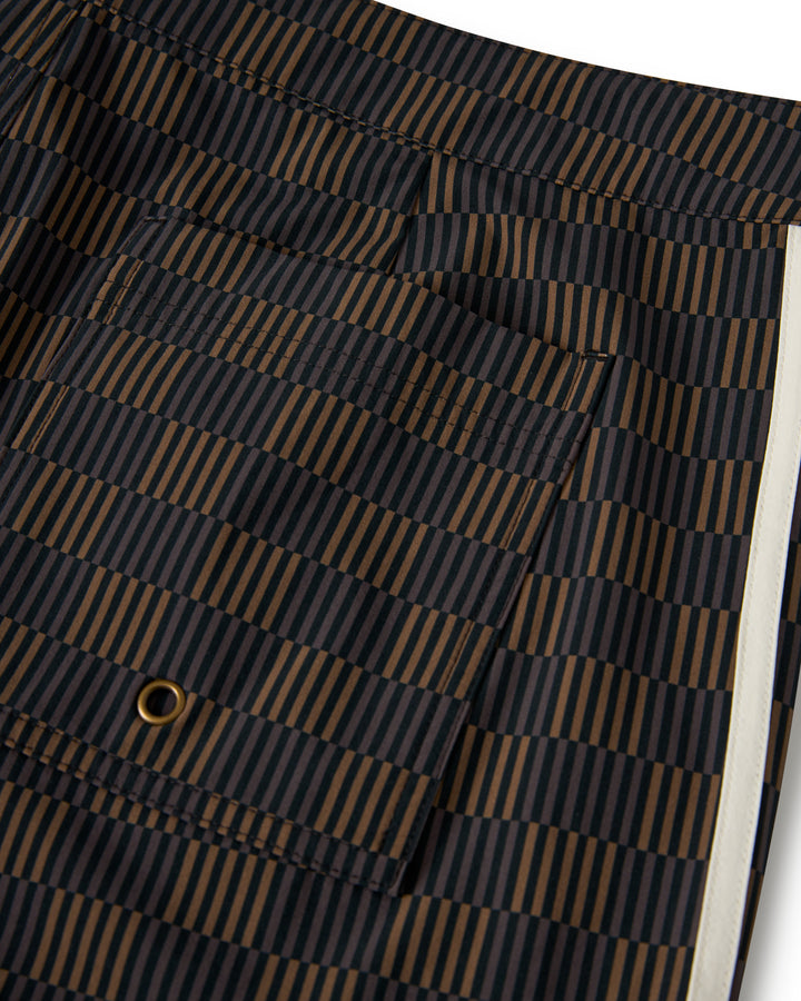 Close-up of The Stirata Swim Short - Onyx by Dandy Del Mar, featuring black and brown stripes, a pocket, and a white vertical stripe on the right.