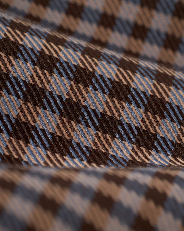 Close-up of The Tresco Shirt - Tierra Houndstooth fabric by Dandy Del Mar featuring a brown, blue, and tan plaid pattern with diagonal lines and texture detail, showcasing casual elegance in every woven thread.