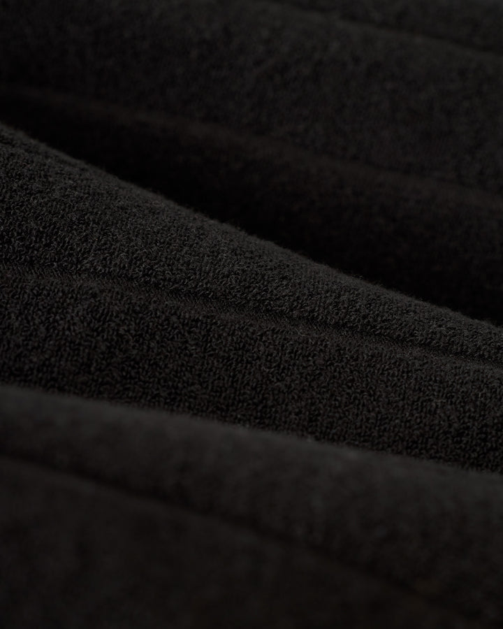 Close-up of The Tropez Terry Cloth Shirt in Onyx by Dandy Del Mar, showcasing its black textured fabric with visible ridges and stitching.