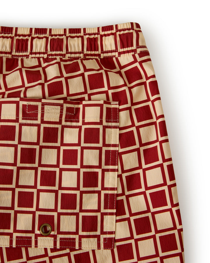 Close-up of The Ventura Volley Short - Rouge by Dandy Del Mar, showcasing a red and beige square pattern with a pocket featuring a small eyelet and button.