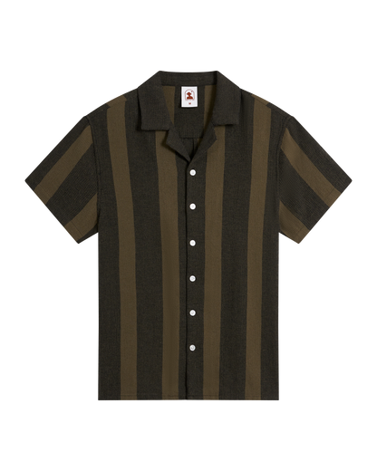 The Palma Shirt - Onyx by Dandy Del Mar is a short-sleeve button-up with dark and light olive green vertical stripes, a camp collar, and white buttons, crafted from burlap-textured fabric and shown on a black background.