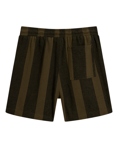 The Palma Short - Onyx by Dandy Del Mar features olive and black stripes, an elastic waistband, and a single back pocket—shown from the back on a black background. Inspired by camp collar shirts and the allure of exotic spices.