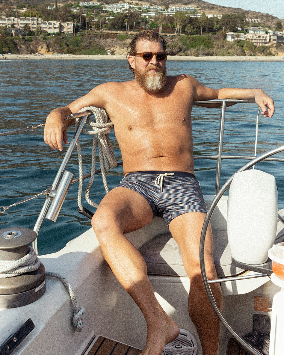 man with wearing shorts of dandy del mar is seating on the boat