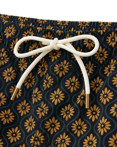Close-up of a drawstring tied in a bow on the elastic waist of The Ventura Volley Shorts in Oro Gardenia Print by Dandy Del Mar, showcasing stylish men's swimwear with yellow and green floral patterns.