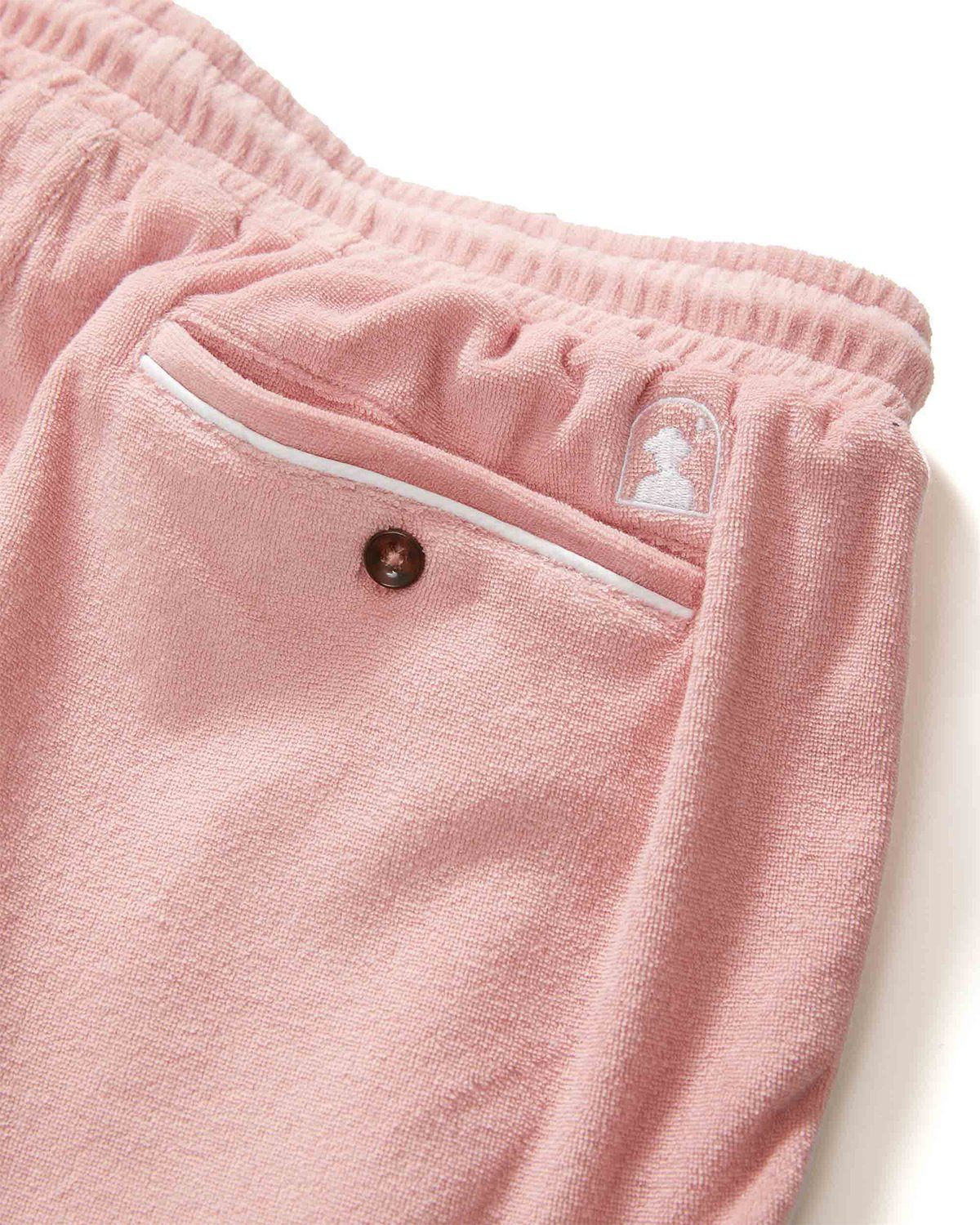 Close-up of The Gaucho Shorts - Mauve by Dandy Del Mar, highlighting their comfortable design with an elastic waistband, snap-buttoned back pocket, and a small embroidered logo above the pocket.